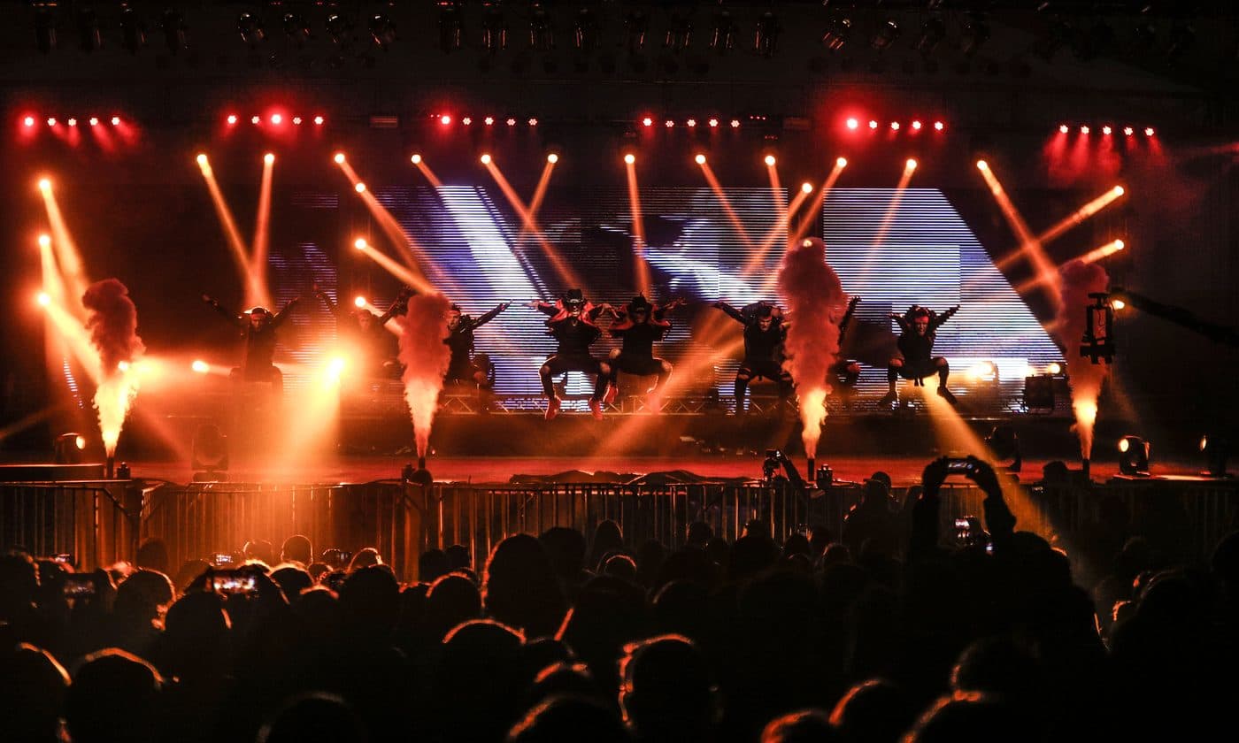Show no palco com faíscas frias e luzes laranja diante do público